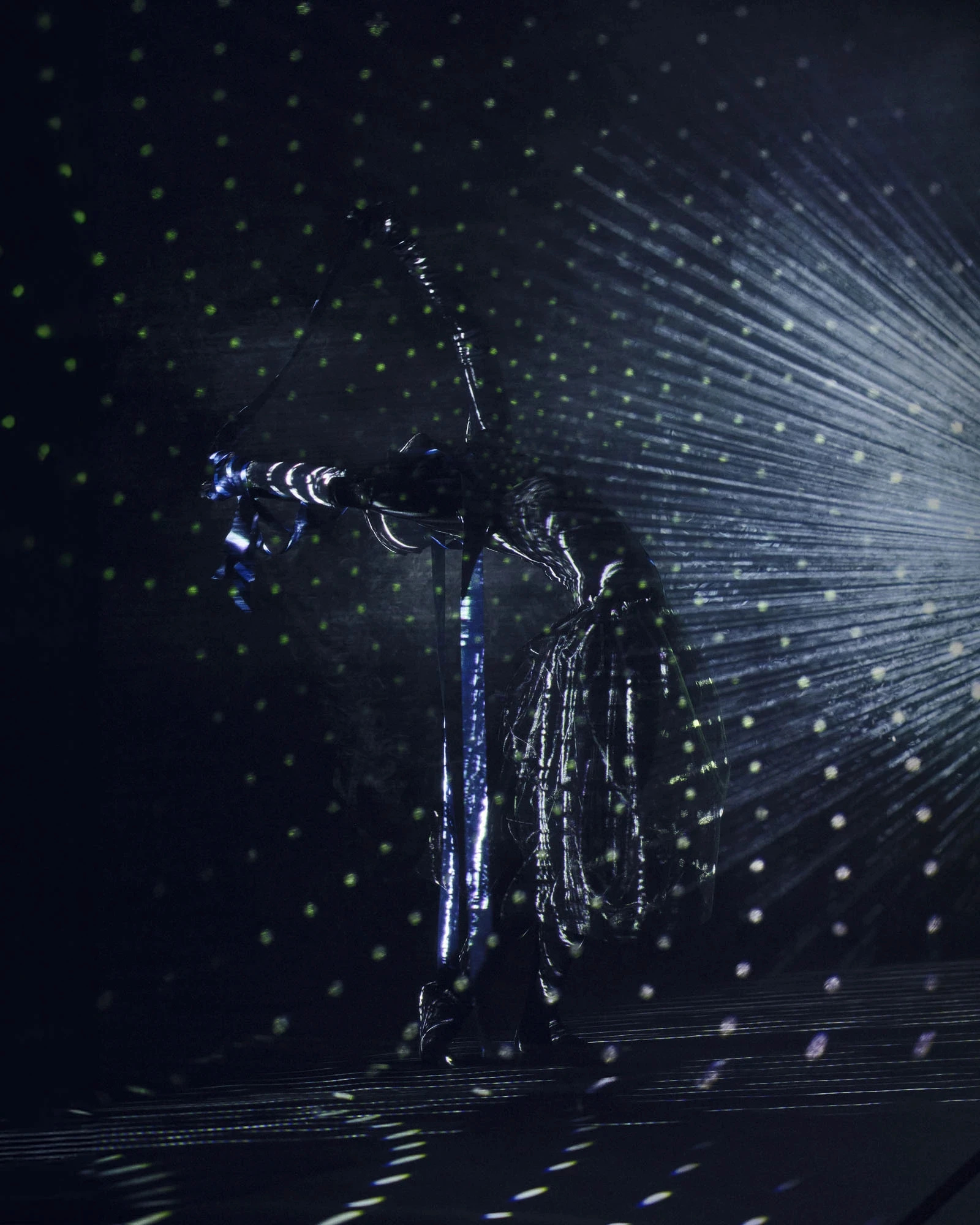 A dancer bent forward in the dark, lines of light radiating from her back
